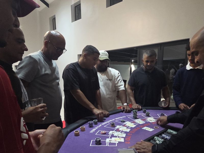 Guests standing around a blackjack table as the dealer plays a hand