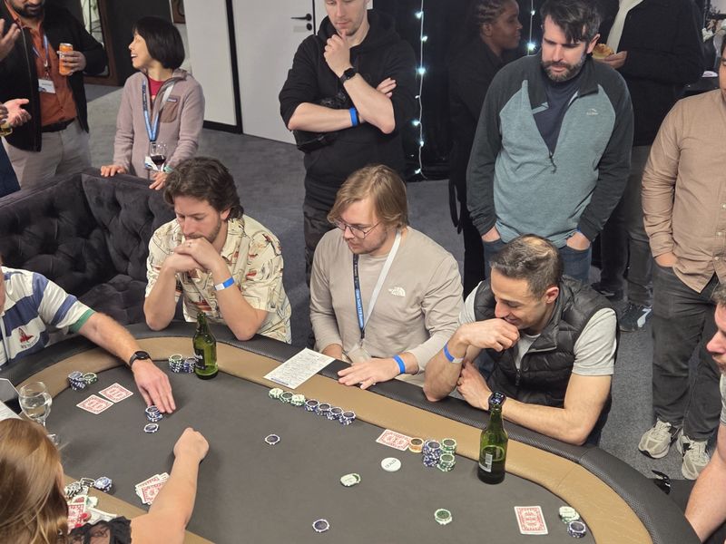 Colleagues and onlookers around a poker table at a corporate fun casino event