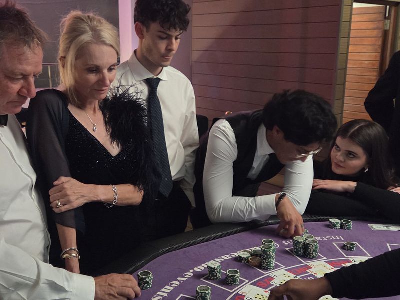 Croupier dealing blackjack as guests in evening wear watch the table
