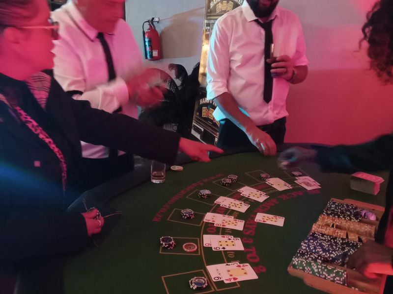 Croupier dealing blackjack under pink party lighting with a slot machine behind