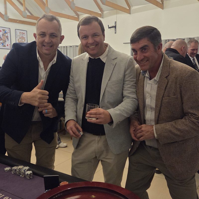 Three smiling guests at a roulette table during a fun casino night in a timber-beamed hall